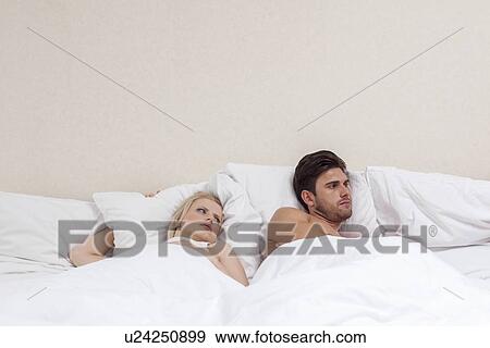 Angry young man ignoring woman in bed View Large Photo Image Stock Photo - Angry young man ignoring woman in bed. Fotosearch