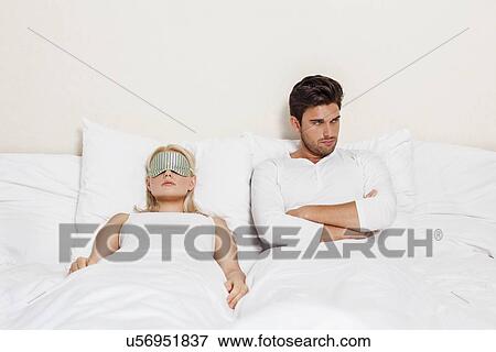 Angry young man with woman sleeping in bed View Large Photo Image Stock Photo - Angry young man with woman sleeping in bed. Fotosearch