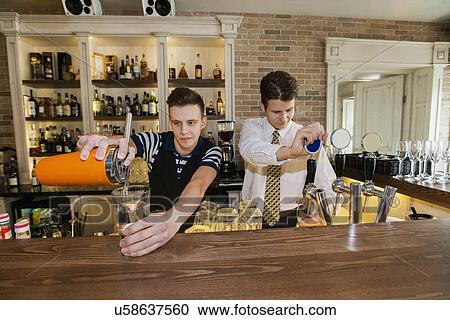 Stock Image - Bartenders working at counter in restaurant. Fotosearch