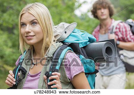 Beautiful female backpacker looking away with man in background at forest View Large Photo Image Stock Image - Beautiful female backpacker looking away with man in background at forest. Fotosearch