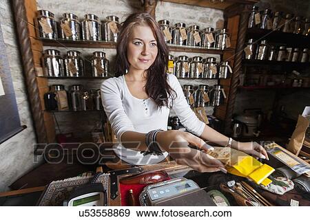 Stock Photo - Beautiful salesperson handing paper bag filled with tea in store. Fotosearch