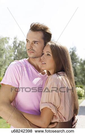 Beautiful young couple looking away in park View Large Photo Image Stock Photo - Beautiful young couple looking away in park. Fotosearch