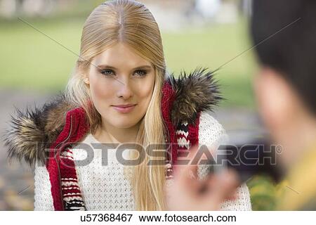 Stock Photo - Beautiful young woman being photographed by man in park. Fotosearch