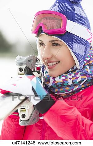 Stock Photograph - Beautiful young woman carrying skis outdoors. Fotosearch