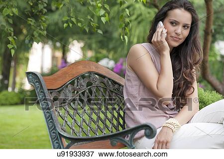 Beautiful young woman looking away while on call in park View Large Photo Image Stock Photo - Beautiful young woman looking away while on call in park. Fotosearch