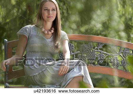 Beautiful young woman sitting on bench in park View Large Photo Image Stock Photograph - Beautiful young woman sitting on bench in park. Fotosearch
