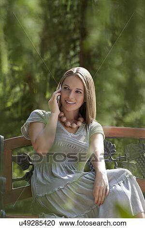 Beautiful young woman using mobile phone on park bench View Large Photo Image Stock Image - Beautiful young woman using mobile phone on park bench. Fotosearch