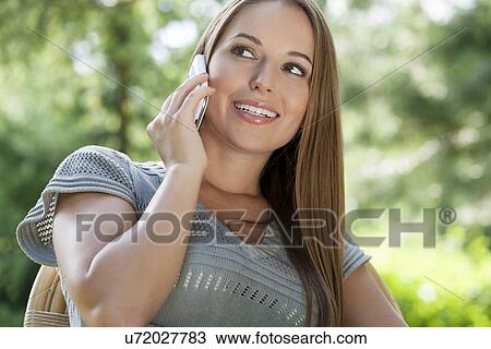 Beautiful young woman using mobile phone in park View Large Photo Image Stock Image - Beautiful young woman using mobile phone in park. Fotosearch