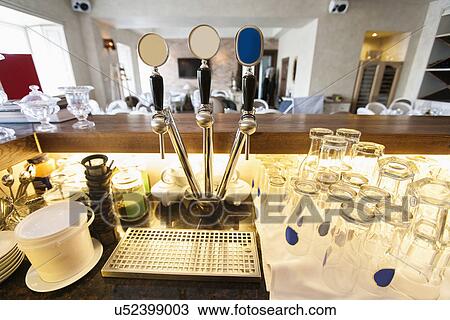 Stock Image - Beer taps and glasses at bar counter. Fotosearch