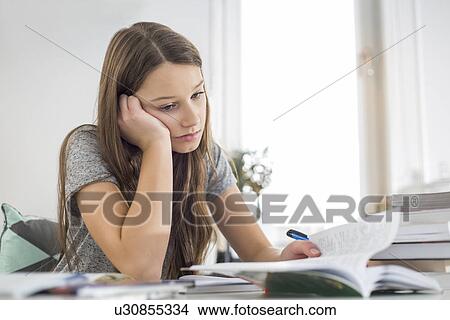 Bored girl studying at table in house View Large Photo Image Picture - Bored girl studying at table in house. Fotosearch