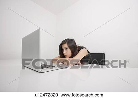 Bored young businesswoman looking at laptop in office View Large Photo Image Stock Image - Bored young businesswoman looking at laptop in office. Fotosearch