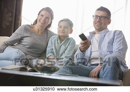 Boy watching TV with parents in living room View Large Photo Image Stock Image - Boy watching TV with parents in living room. Fotosearch
