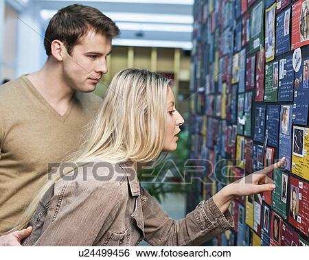 Stock Photograph - Business couple reading information about models on board in office. Fotosearch