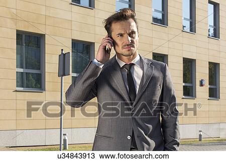 Businessman using cell phone against office building View Large Photo Image Stock Image - Businessman using cell phone against office building. Fotosearch