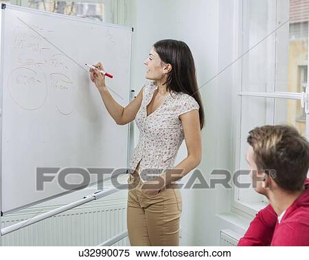 Stock Photography - Businesswoman writing on whiteboard in meeting. Fotosearch