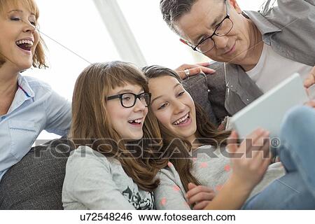 Cheerful family using tablet PC at home View Large Photo Image Stock Photograph - Cheerful family using tablet PC at home. Fotosearch