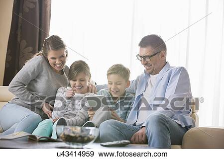 Cheerful family using tablet PC together in living room View Large Photo Image Stock Photo - Cheerful family using tablet PC together in living room. Fotosearch