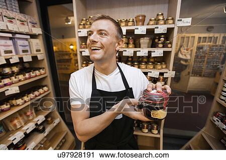 Cheerful salesman holding jar of jam in grocery store View Large Photo Image Stock Image - Cheerful salesman holding jar of jam in grocery store. Fotosearch