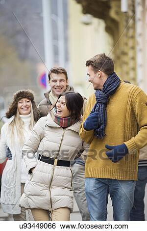 Stock Photograph - Cheerful young couples in warm clothing on city street. Fotosearch