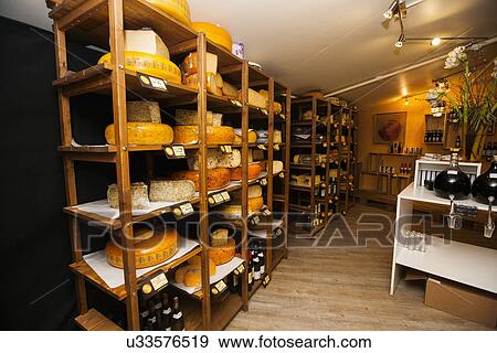 Stock Photo - Cheese arranged on shelves in shop. Fotosearch