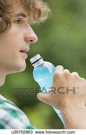 Close-up of man drinking energy drink outdoors View Large Photo Image Stock Image - Close-up of man drinking energy drink outdoors. Fotosearch