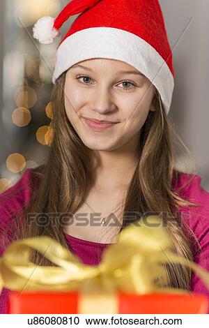 Stock Image - Close-up portrait of smiling girl wearing Santa hat. Fotosearch