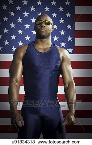 Confident male runner standing against American flag View Large Photo Image Stock Photo - Confident male runner standing against American flag. Fotosearch