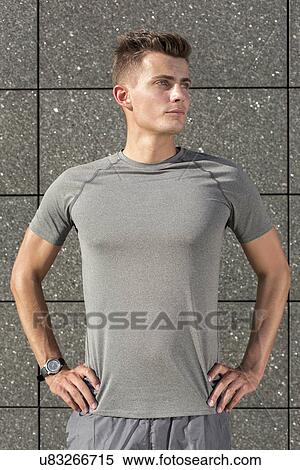 Confident young jogger standing hands on hips against tiled wall View Large Photo Image Stock Photography - Confident young jogger standing hands on hips against tiled wall. Fotosearch