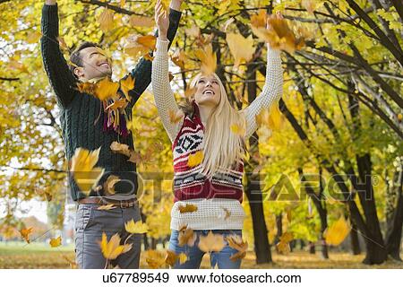 Stock Photo - Couple enjoying falling autumn leaves in park. Fotosearch