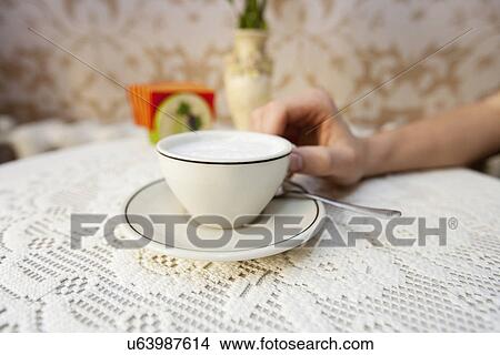 Picture - Cropped image of man having cup of coffee at table in cafe. Fotosearch