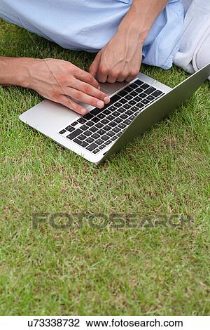 Cropped image of man using laptop on grass in park View Large Photo Image Stock Image - Cropped image of man using laptop on grass in park. Fotosearch