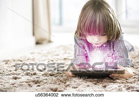 Cute boy using illuminated tablet while lying on rug at home View Large Photo Image Stock Image - Cute boy using illuminated tablet while lying on rug at home. Fotosearch