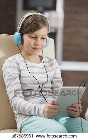 Cute girl listening music while using digital tablet at home View Large Photo Image Stock Image - Cute girl listening music while using digital tablet at home. Fotosearch
