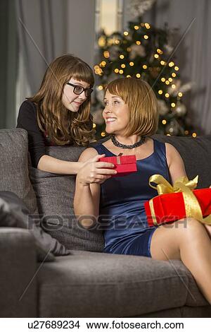 Picture - Daughter giving Christmas present to mother at home. Fotosearch