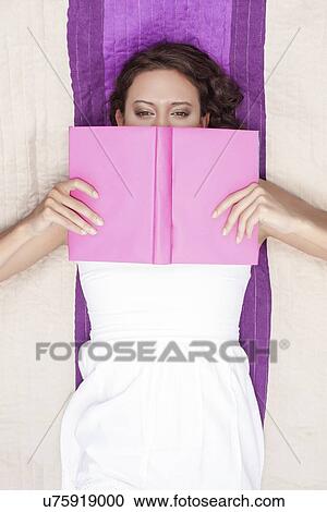 Directly above shot of woman covering face with book while lying on picnic blanket View Large Photo Image Stock Image - Directly above shot of woman covering face with book while lying on picnic blanket. Fotosearch