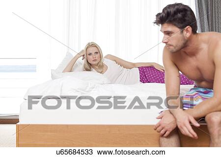 Displeased young couple on bed in hotel room View Large Photo Image Stock Image - Displeased young couple on bed in hotel room. Fotosearch