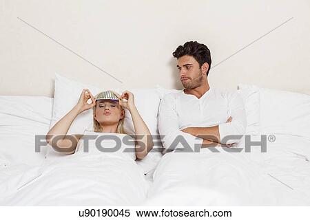 Displeased young man looking at woman wearing eye mask in bed View Large Photo Image Stock Photography - Displeased young man looking at woman wearing eye mask in bed. Fotosearch