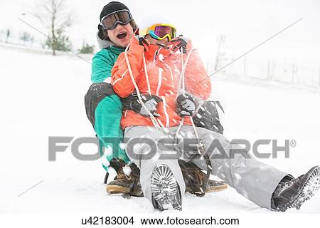 Excited young couple sledding in snow View Large Photo Image Picture - Excited young couple sledding in snow. Fotosearch