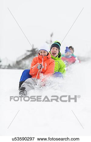 Excited young friends sledding in snow View Large Photo Image Stock Photo - Excited young friends sledding in snow. Fotosearch