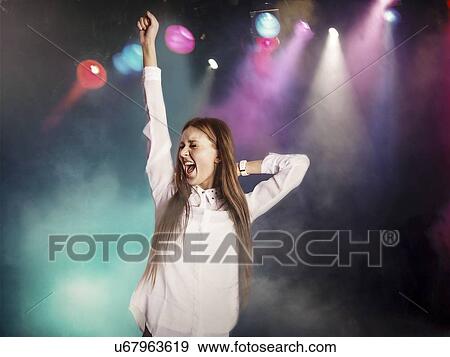 Excited young woman dancing in nightclub View Large Photo Image Stock Photo - Excited young woman dancing in nightclub. Fotosearch