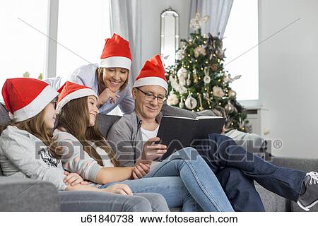 Family of four reading book in living room during Christmas View Large Photo Image Stock Photo - Family of four reading book in living room during Christmas. Fotosearch