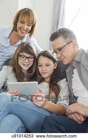Family using digital tablet together in living room View Large Photo Image Stock Image - Family using digital tablet together in living room. Fotosearch