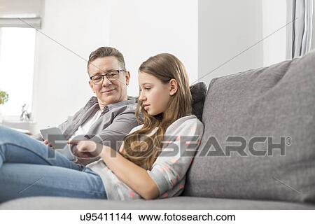 Father and daughter using digital tablet on sofa at home View Large Photo Image Picture - Father and daughter using digital tablet on sofa at home. Fotosearch