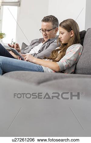 Father and daughter using digital tablet together at home View Large Photo Image Stock Photograph - Father and daughter using digital tablet together at home. Fotosearch