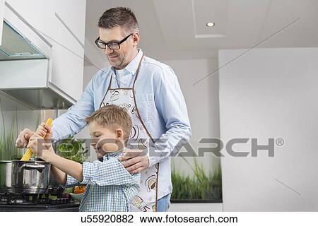 Stock Image - Father and son preparing spaghetti in kitchen. Fotosearch