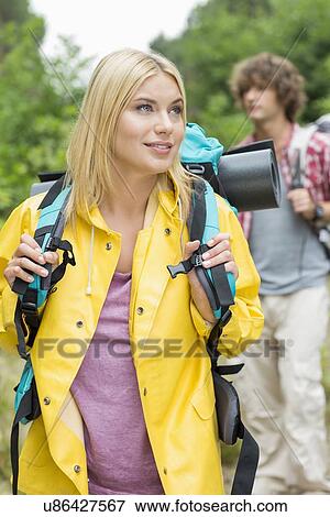 Female backpacker with man standing in background at forest View Large Photo Image Stock Photo - Female backpacker with man standing in background at forest. Fotosearch