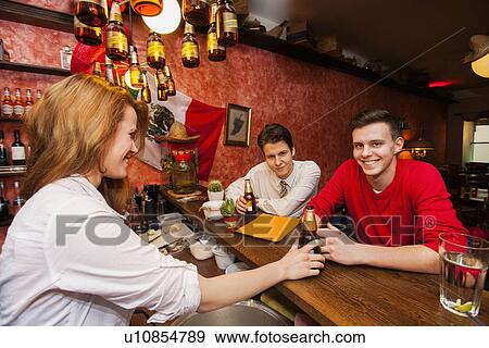Female bartender serving beer to men at bar counter View Large Photo Image Stock Photo - Female bartender serving beer to men at bar counter. Fotosearch