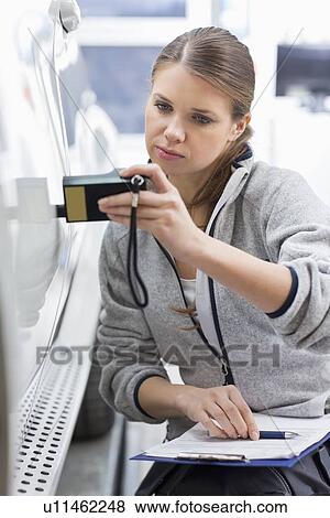 Female maintenance engineer checking car paint with equipment in workshop View Large Photo Image Stock Photo - Female maintenance engineer checking car paint with equipment in workshop. Fotosearch