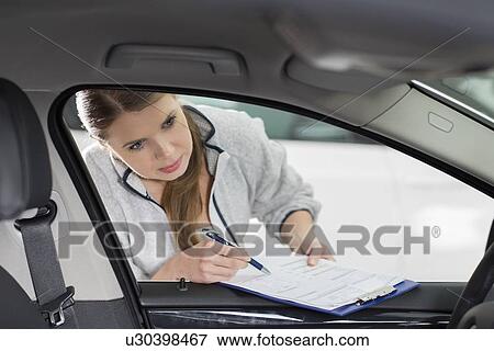 Female maintenance engineer with clipboard examining car's interior in workshop View Large Photo Image Stock Photo - Female maintenance engineer with clipboard examining car's interior in workshop. Fotosearch