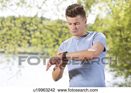 Fit young man checking time at park View Large Photo Image Stock Image - Fit young man checking time at park. Fotosearch